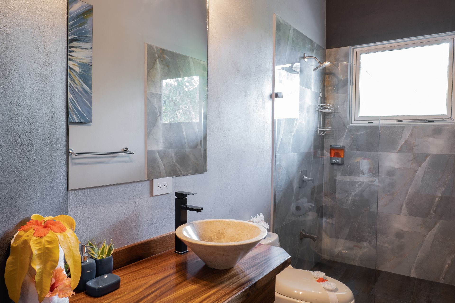 Modern bathroom with glass shower, mirror, black faucet, and wooden vanity with bowl sink