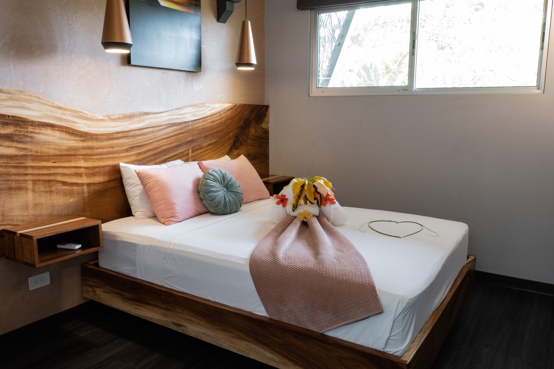 Modern bedroom with a wooden bed, pink bedding, and a window letting in natural light