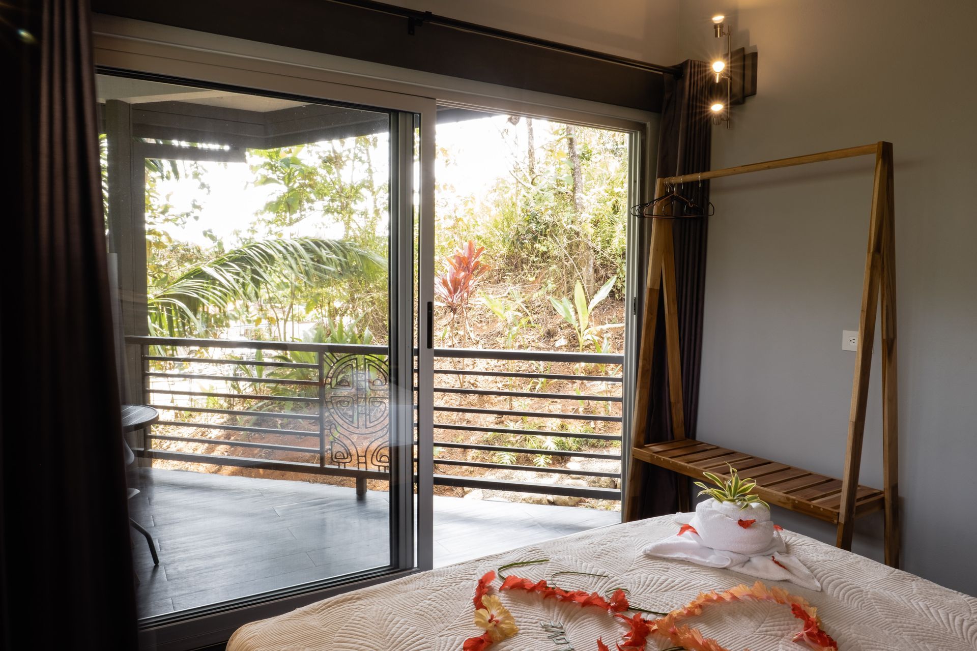 Bedroom with sliding glass doors opening to a balcony and greenery outside