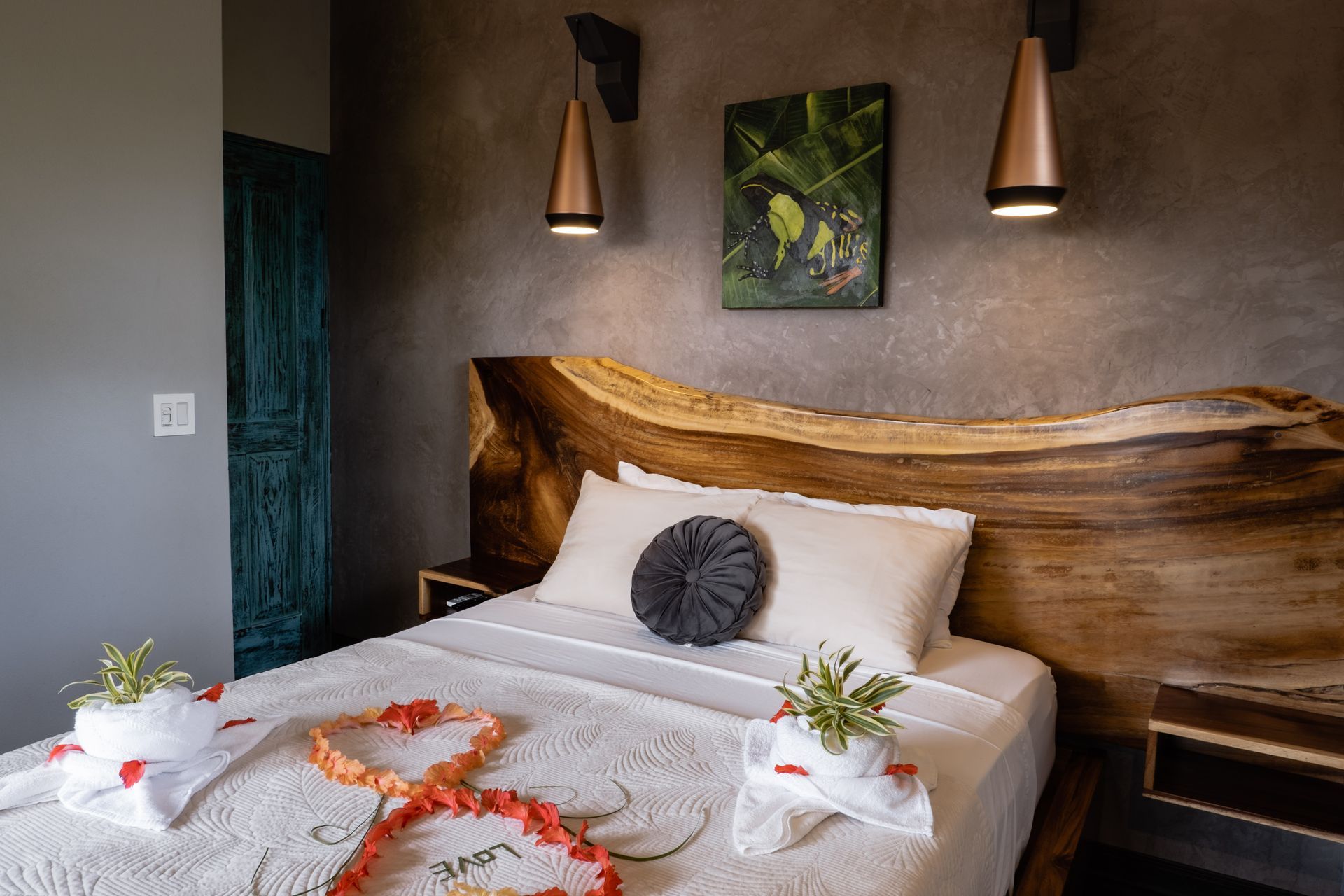 Romantic hotel bed with flower petals, folded towels, and warm wall lamps in a cozy room