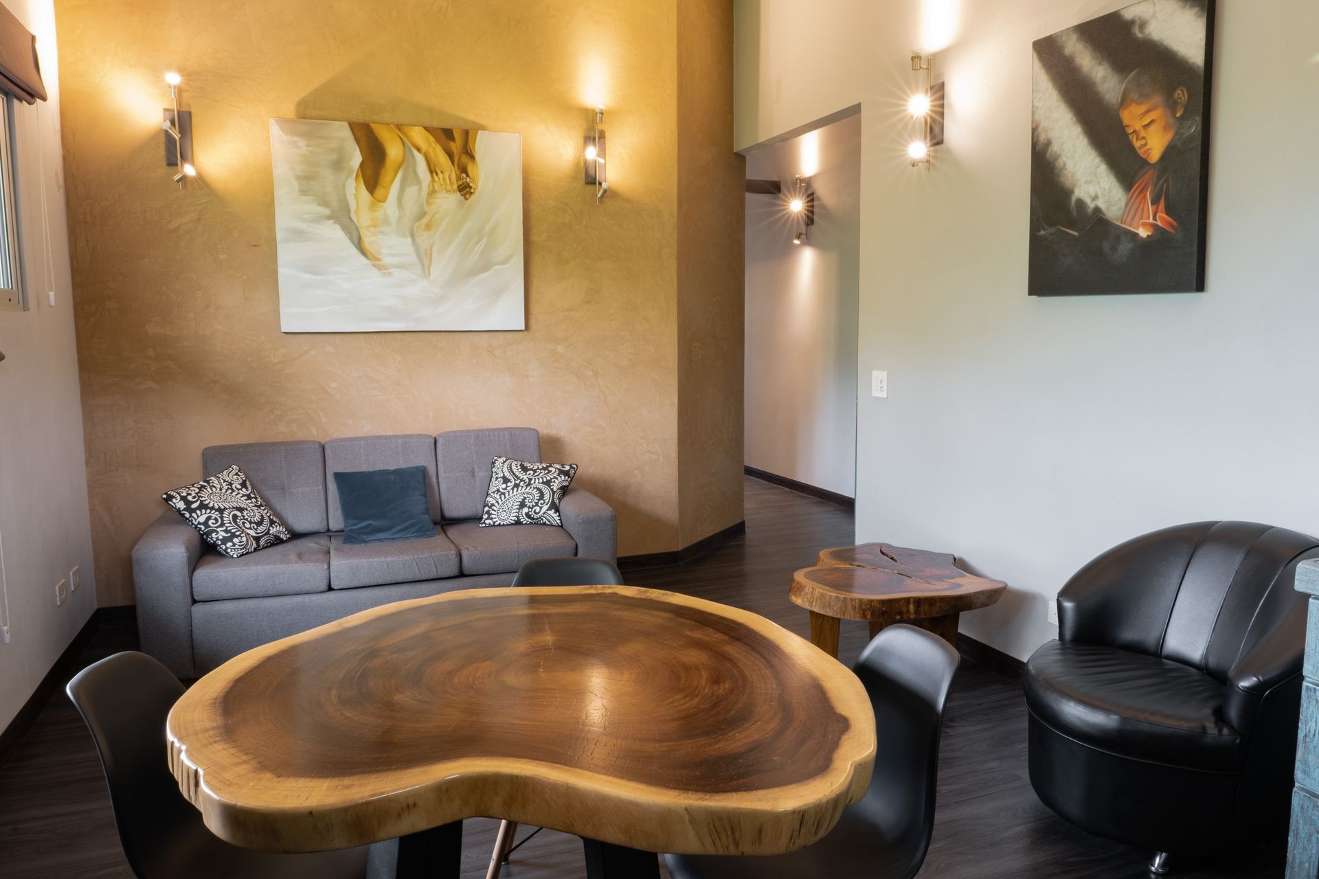 Modern living room with gray sofa, black chairs, and a large wooden coffee table under warm lighting