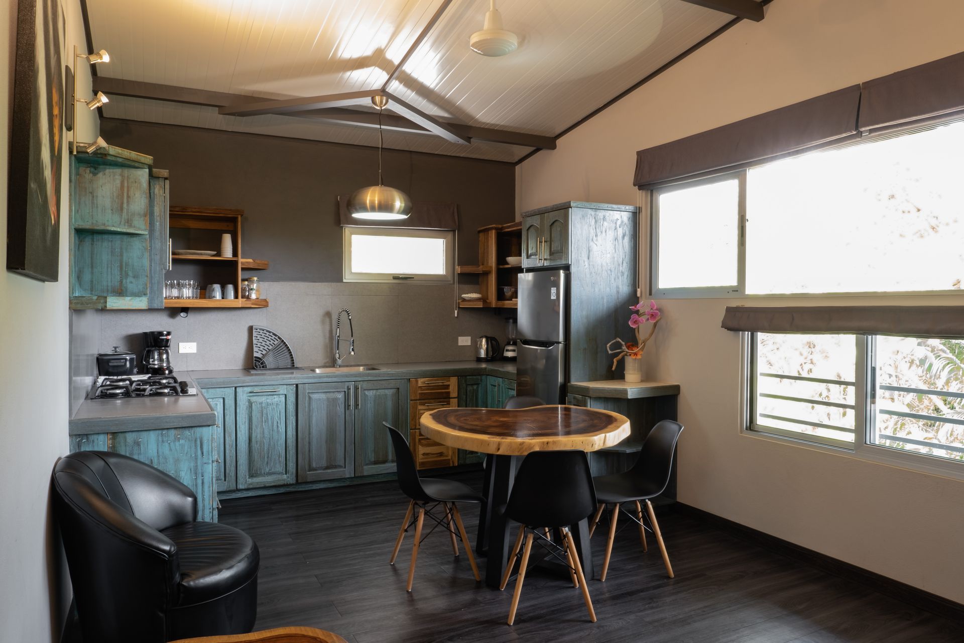 Cozy kitchen-dining area with blue cabinets, round wooden table, black chair, and bright windows