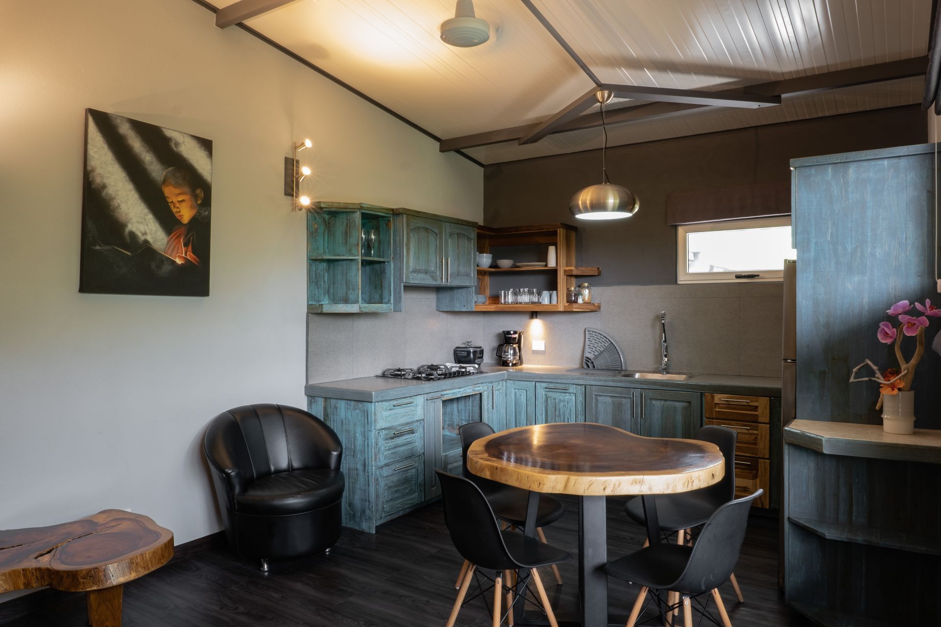 Small rustic kitchen and dining nook with blue cabinets, round wooden table, and black chairs