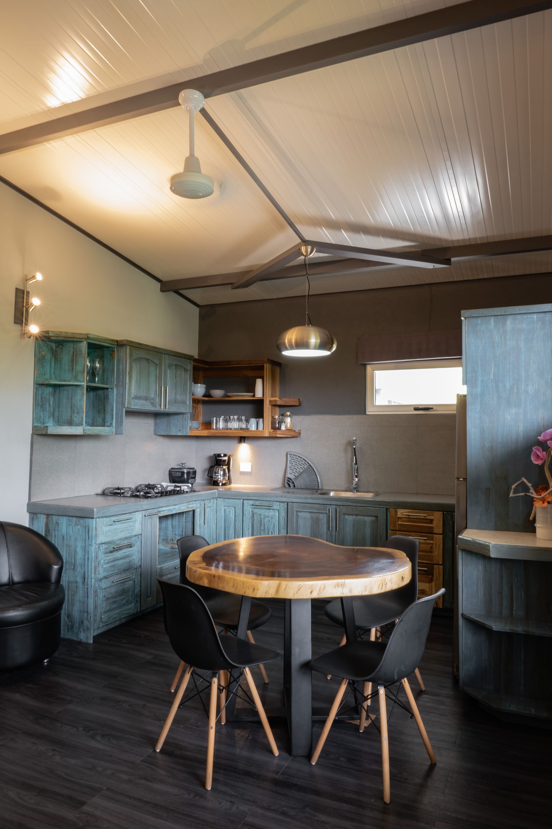 Cozy kitchen with blue cabinets, round wooden table, and pendant lights in a rustic interior.
