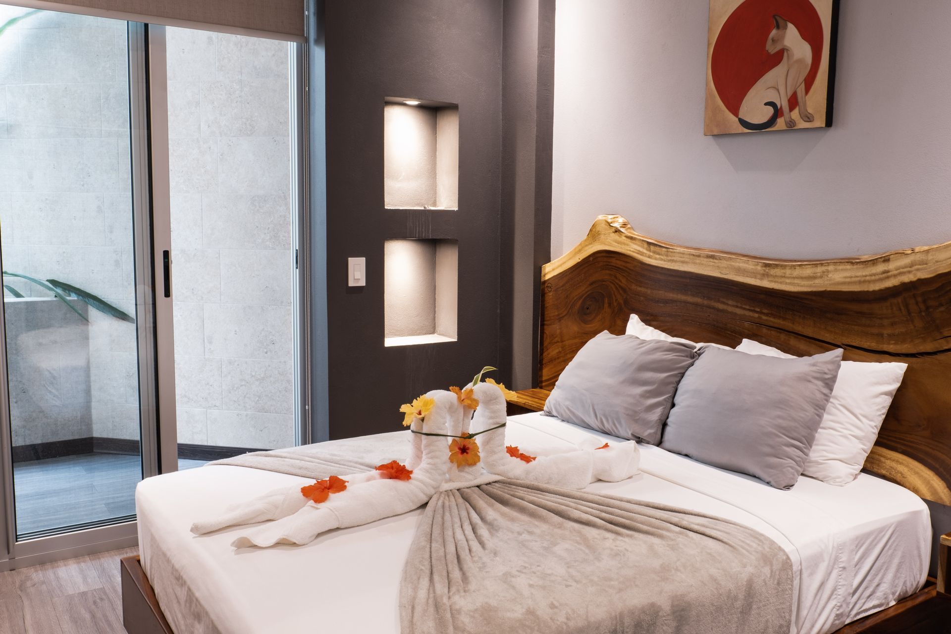 Modern bedroom with a wooden bed, white bedding, and a sliding glass door to a balcony
