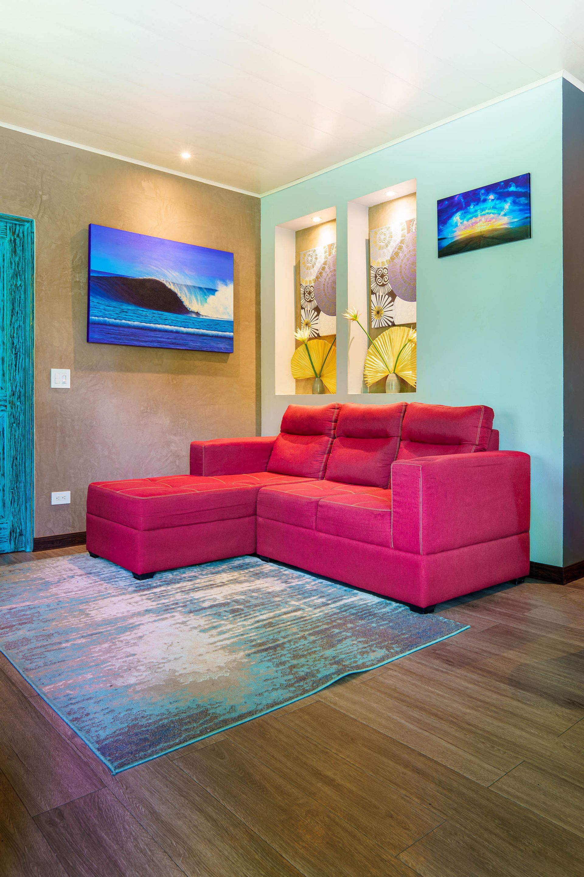 Modern living room with a bright pink sectional, wall art, and a turquoise rug