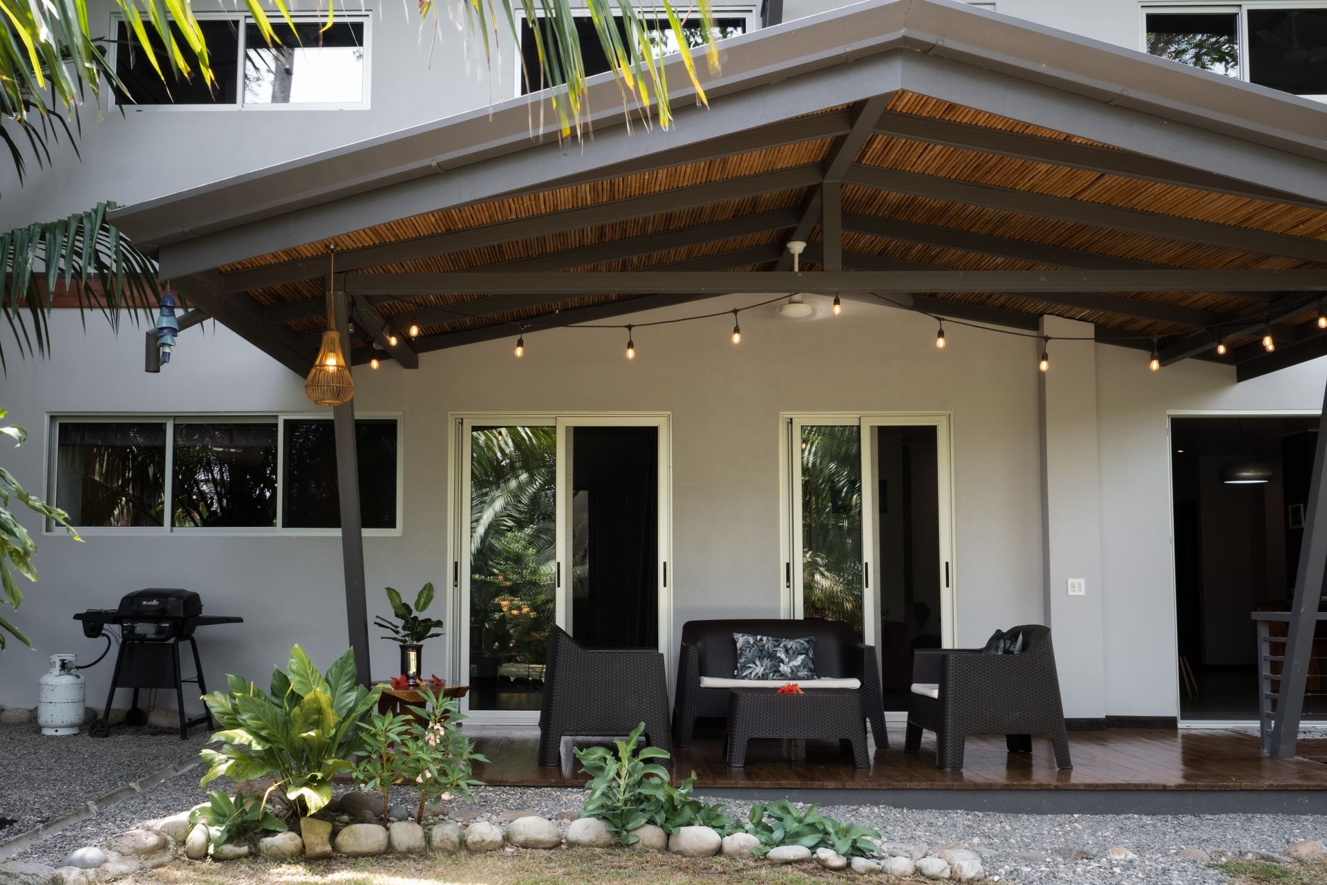 Modern house patio with covered porch, string lights, outdoor seating, and potted plants
