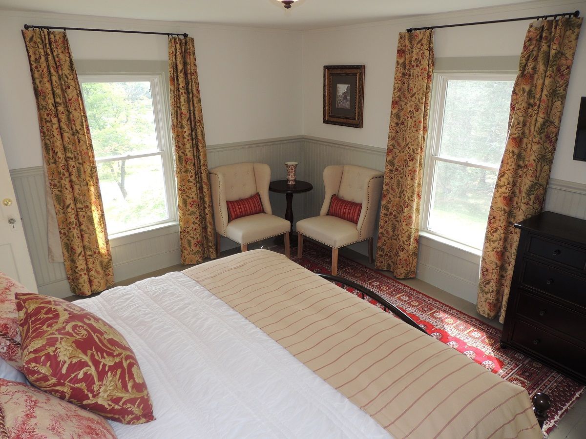 A bedroom with a king size bed and two chairs