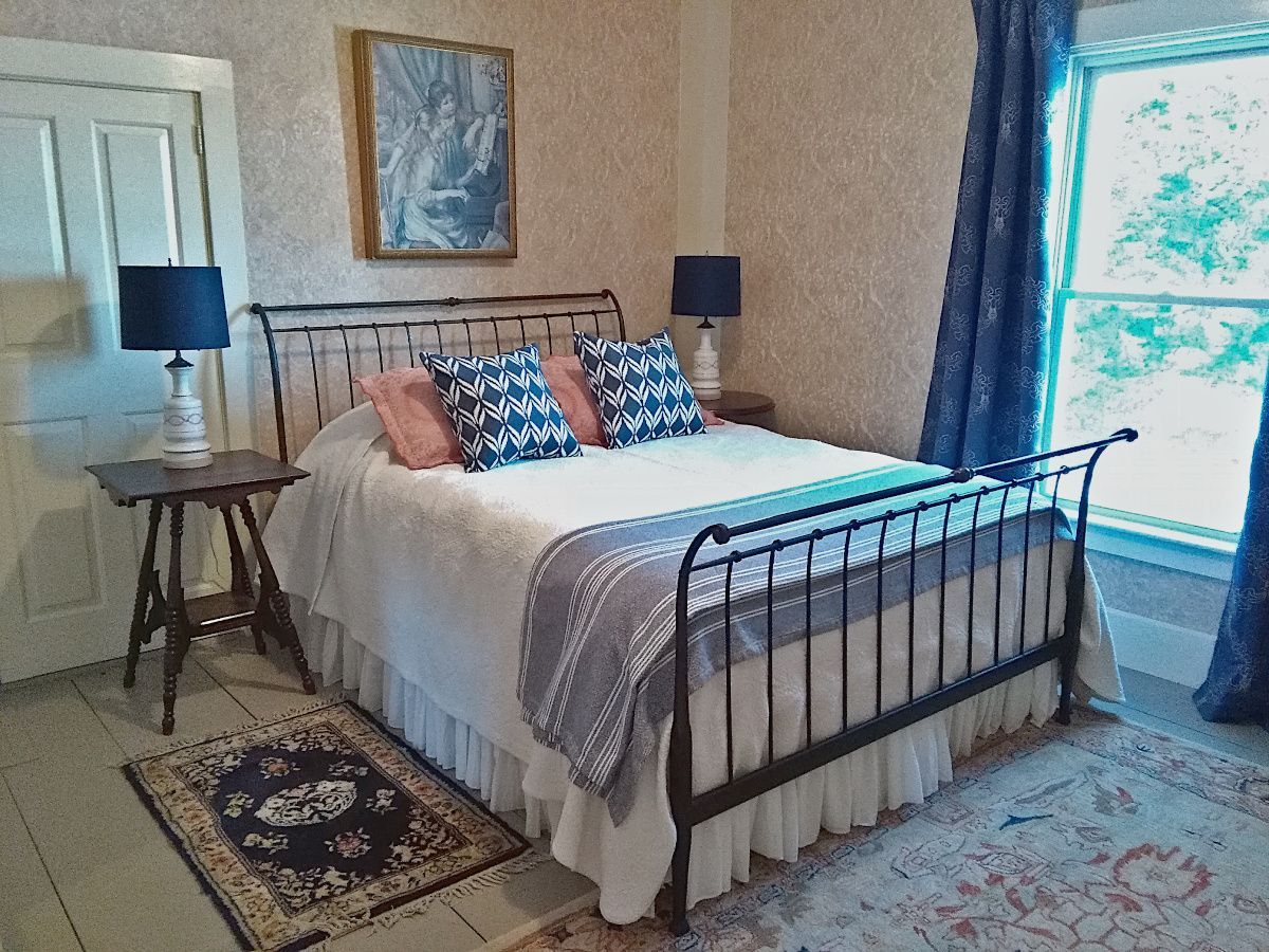 A bedroom with a bed , two lamps , a rug and a window.