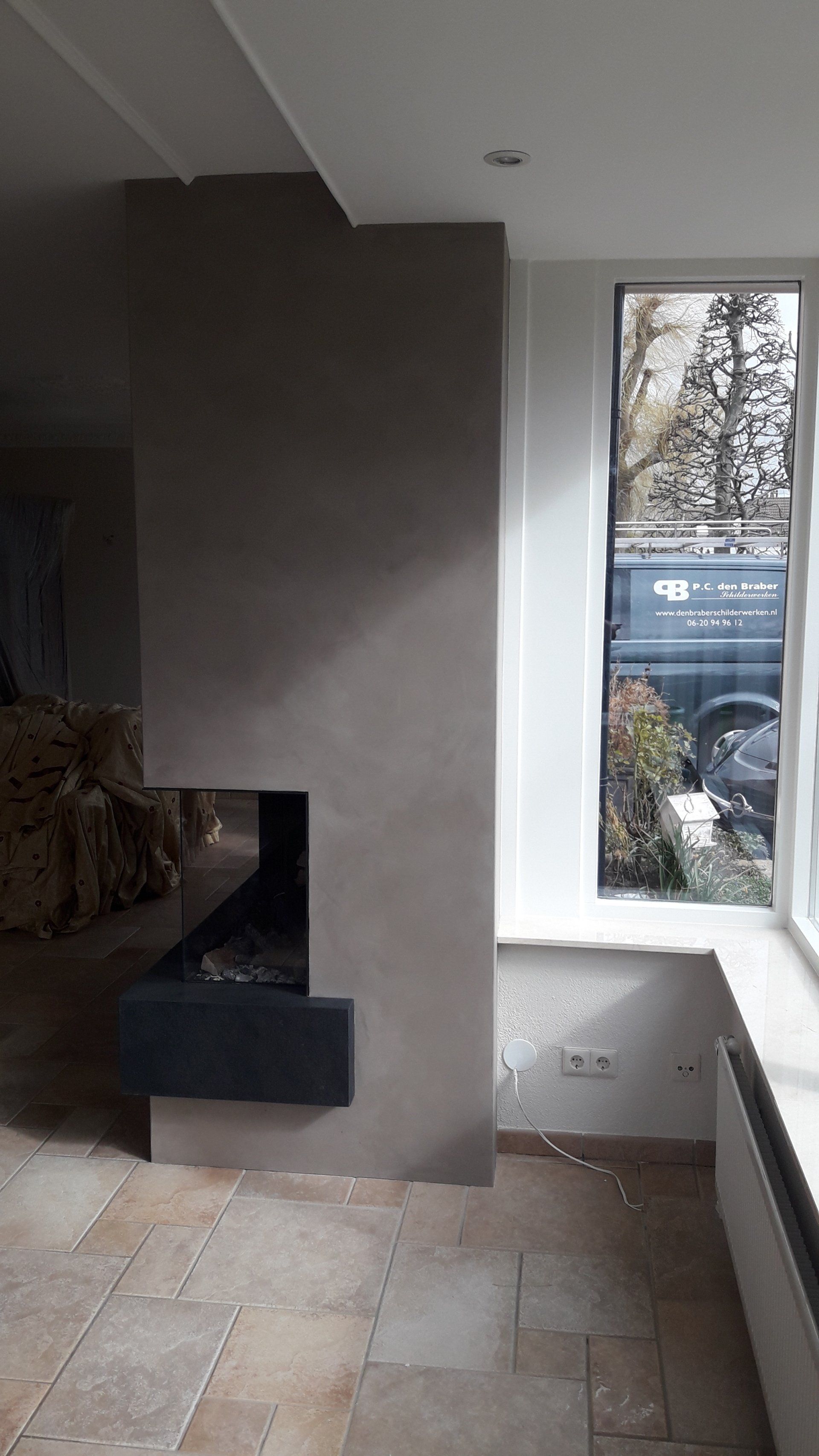 Moderne kamer met een open haard, tegelvloer en een hoog raam.