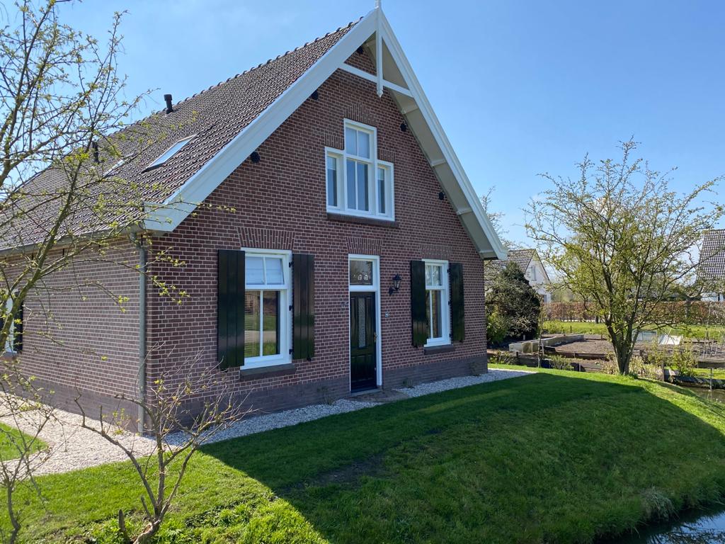 Bakstenen huis met  zadeldak, voorgevel geschilderd.