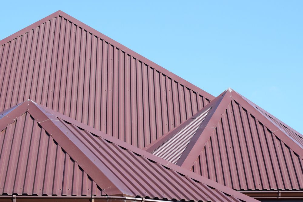 Brown Metal Roof With Vertical Ridges Against a Clear Blue Sky — Coffs Coast Roofing In Sawtell, NSW