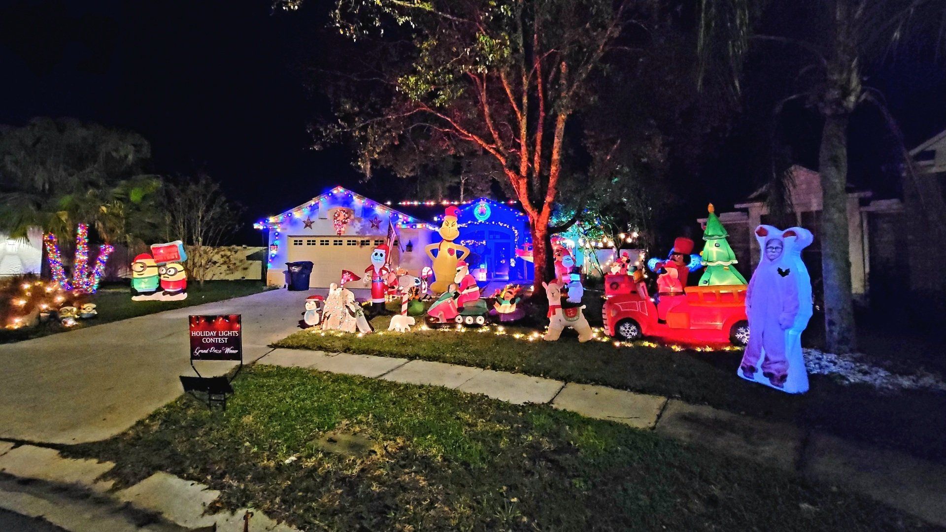 A house is decorated with christmas lights and decorations at night.