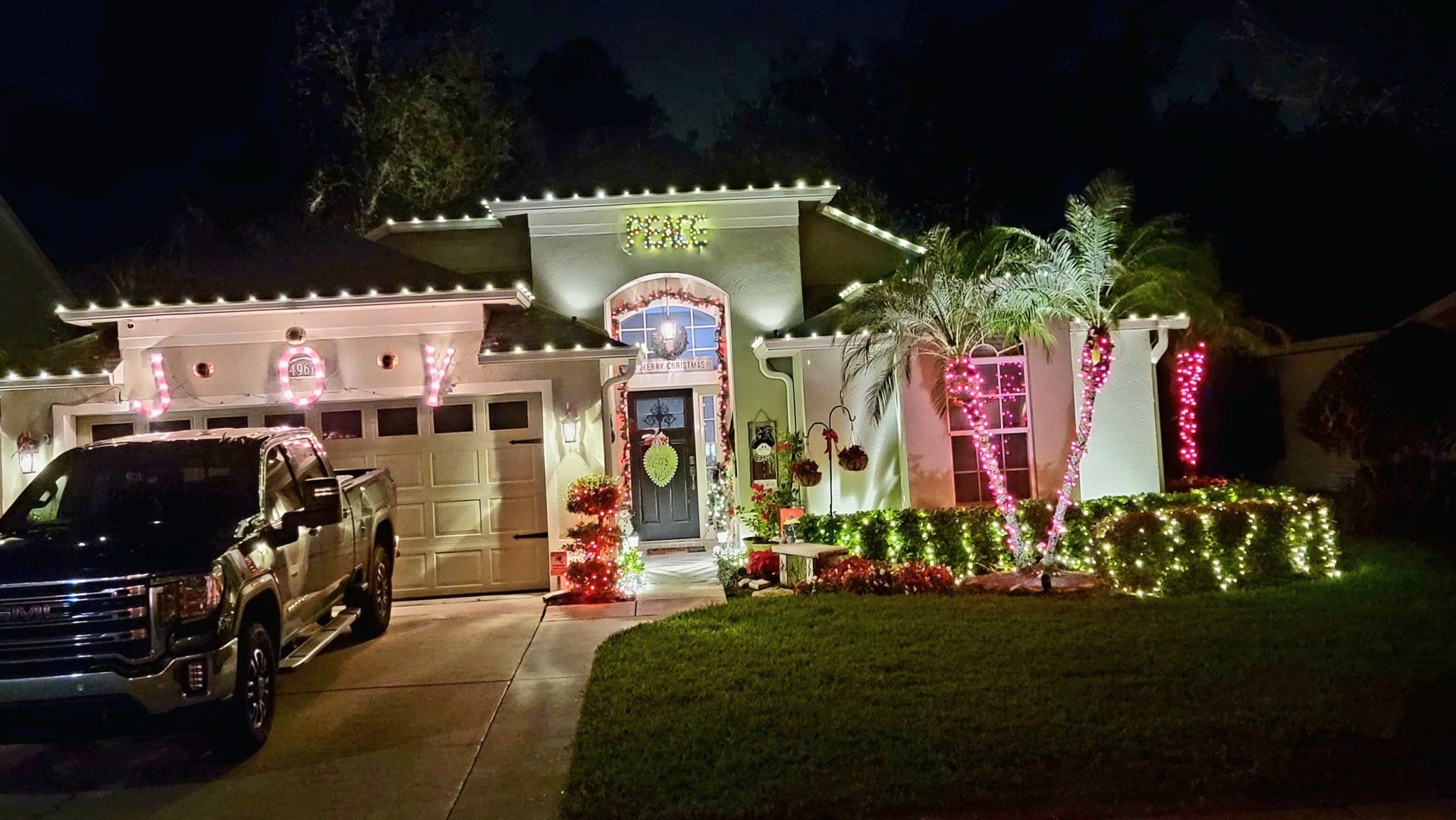 A house decorated for christmas with a truck parked in front of it.