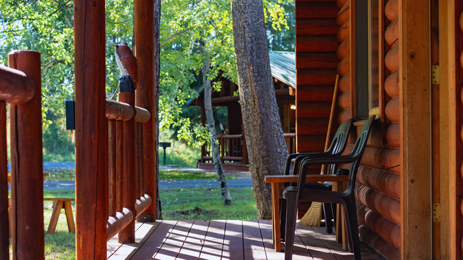 Porch with wooden chairs and columns overlooking a green yard in daylight