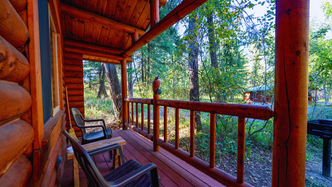 Wooden cabin porch with rocking chairs and forest view through the railing
