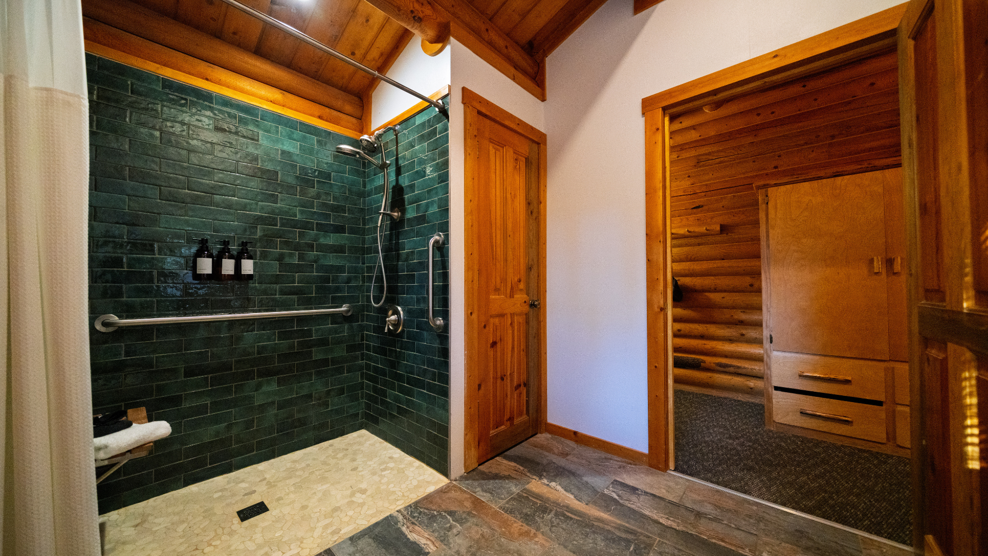 Wood-paneled bathroom with dark green tiled shower and sauna-style wooden door
