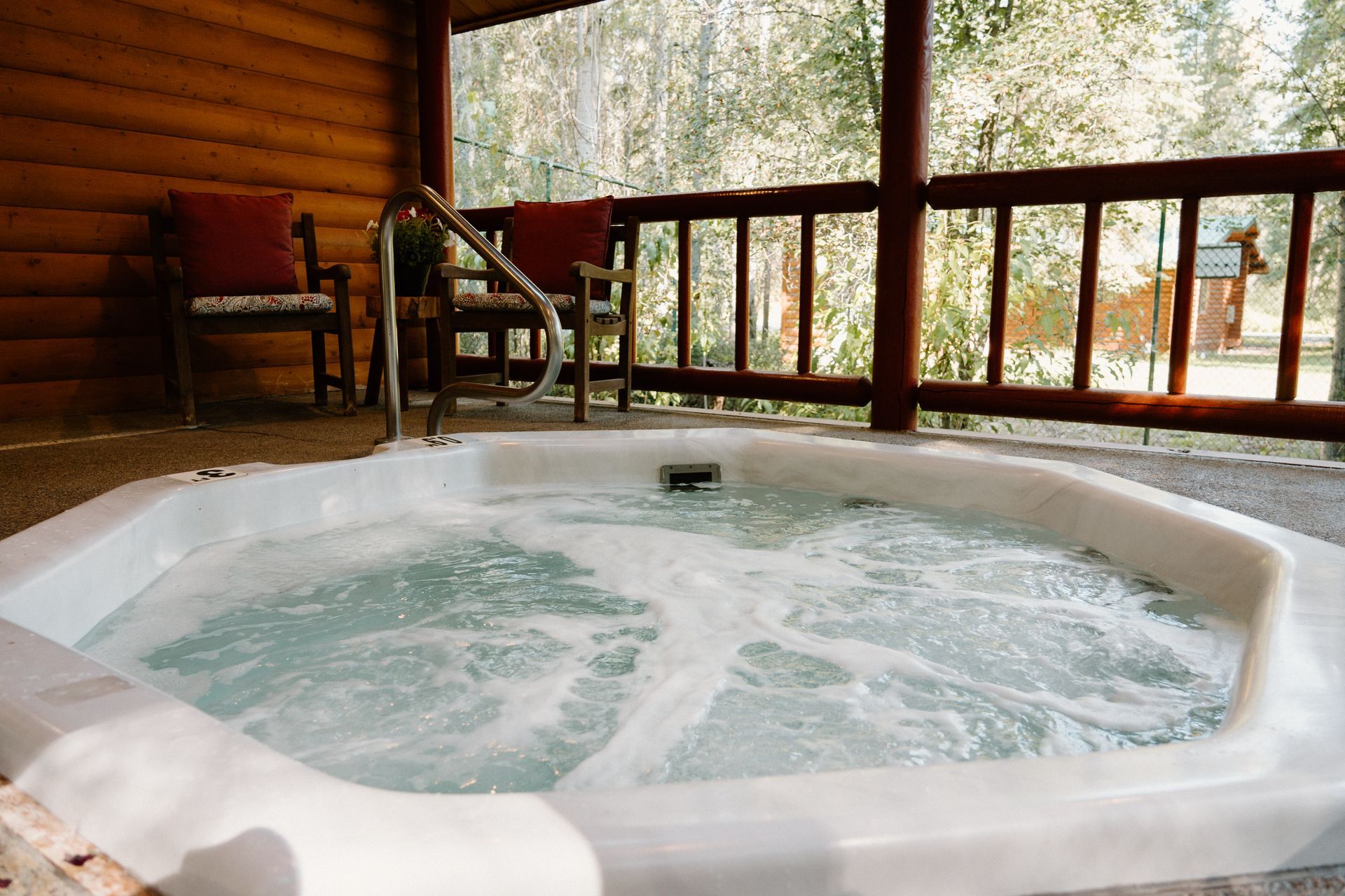 A hot tub is sitting on the porch of a log cabin.