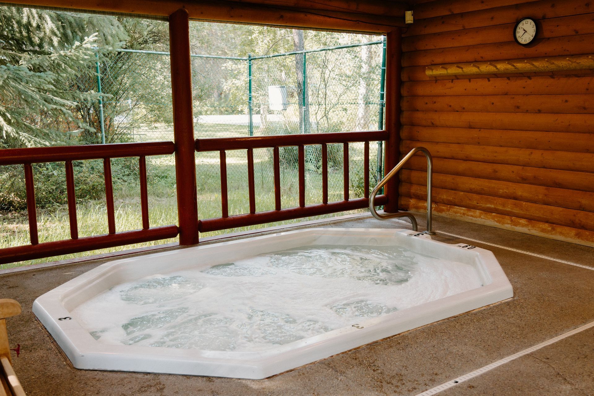 A hot tub in a log cabin with a clock on the wall