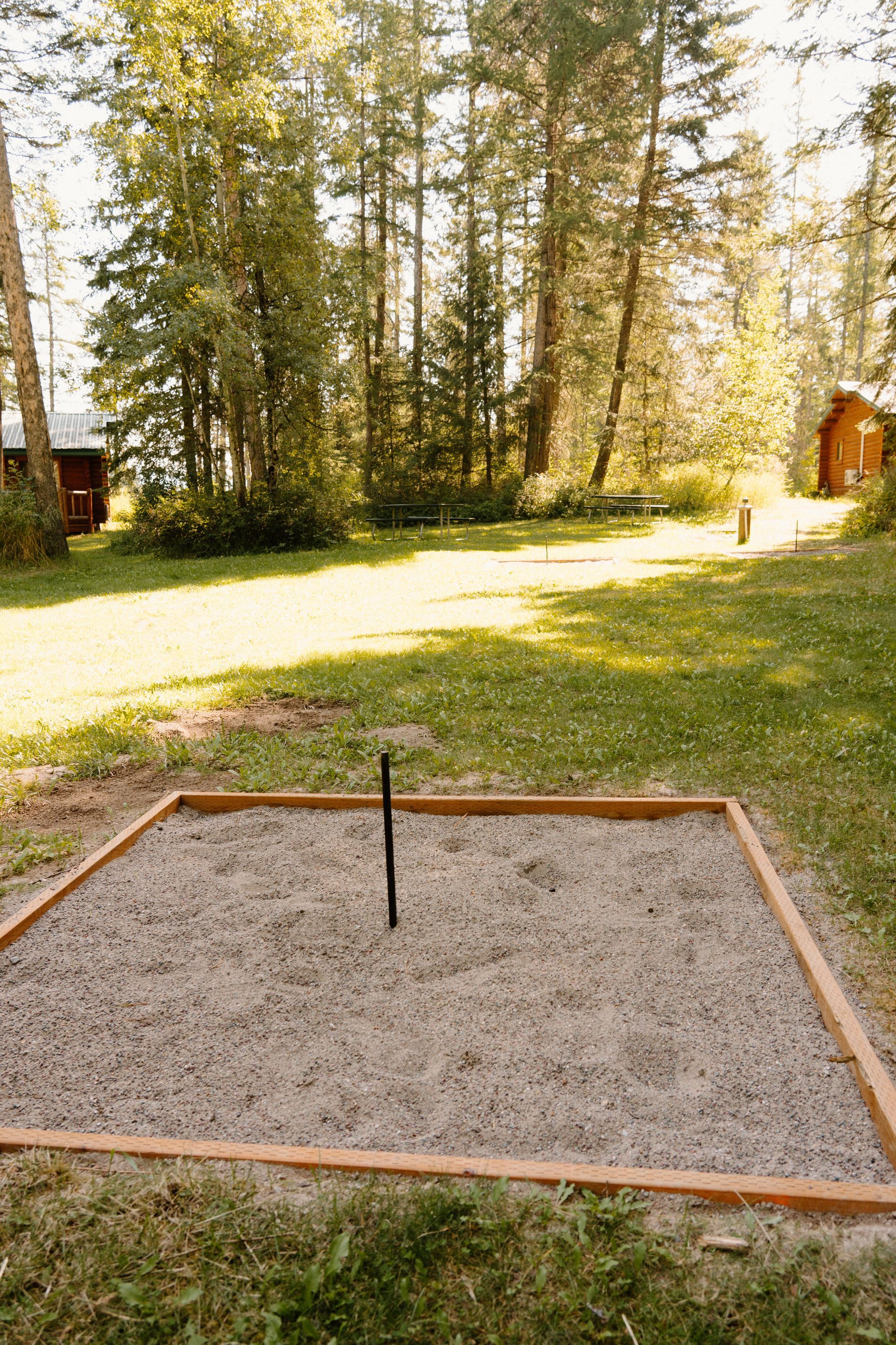 A sandbox in the middle of a lush green field with trees in the background.