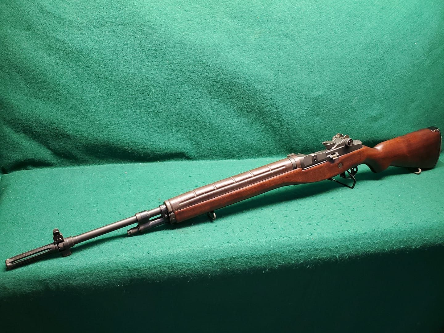 A brown rifle with a wooden stock on a green surface.