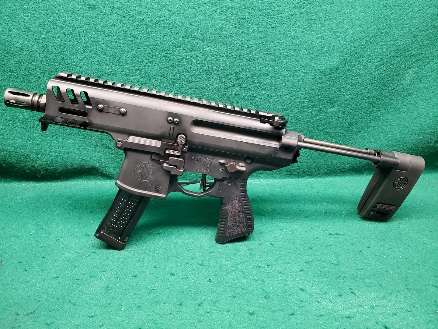 Black submachine gun on a green surface.