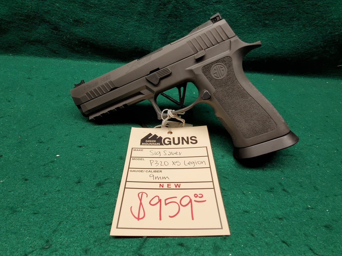 A gray Sig Sauer P320 pistol with a price tag of $959.00 on a green surface.