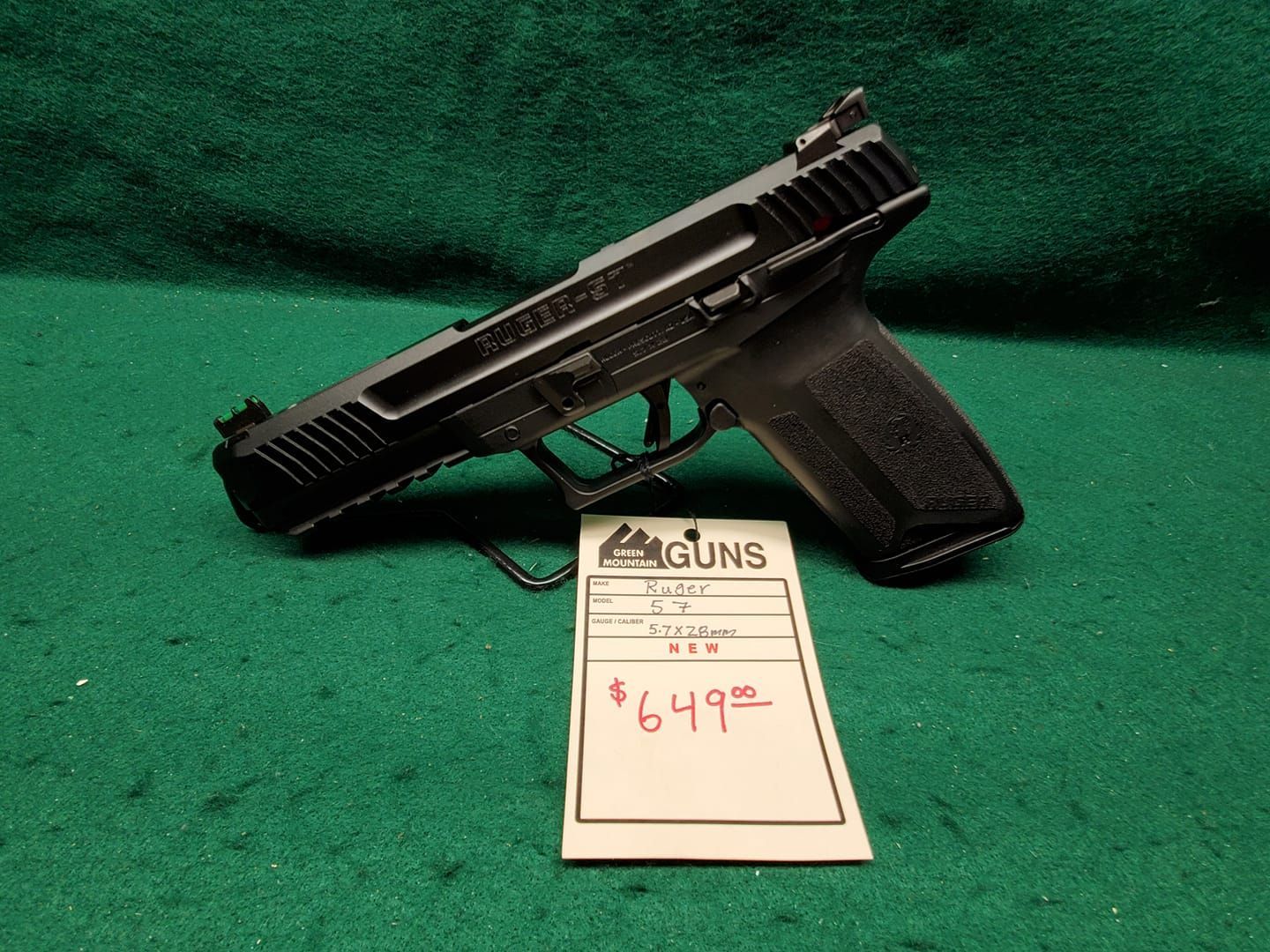 Black handgun on a green surface with a price tag that says $649.98.