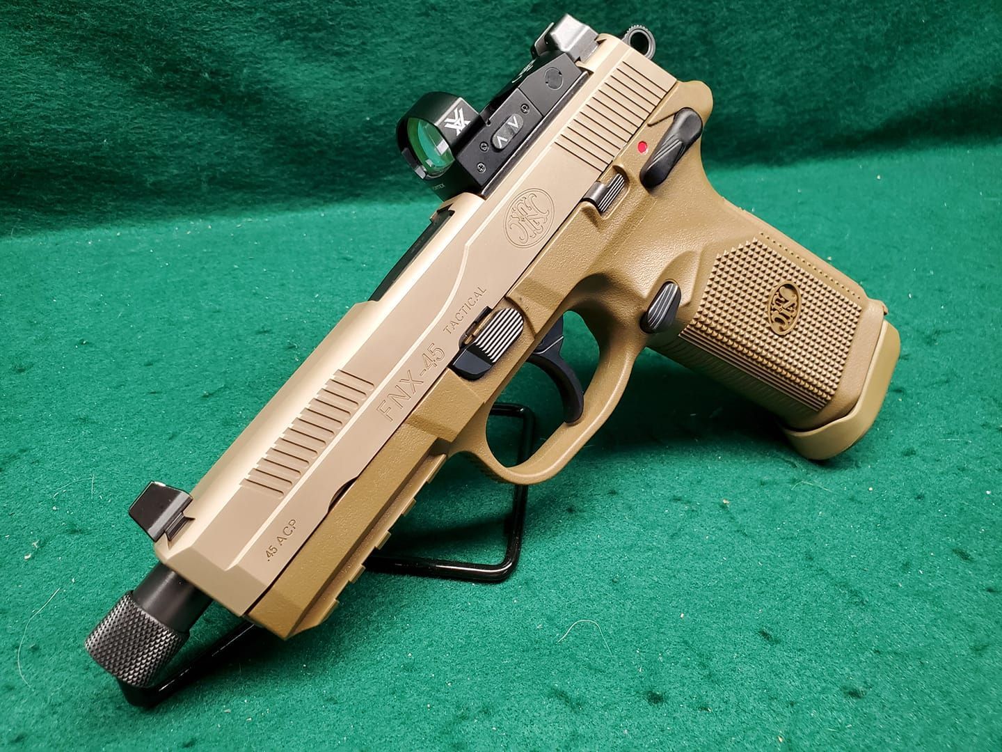 Tan handgun with red dot sight on a green surface.