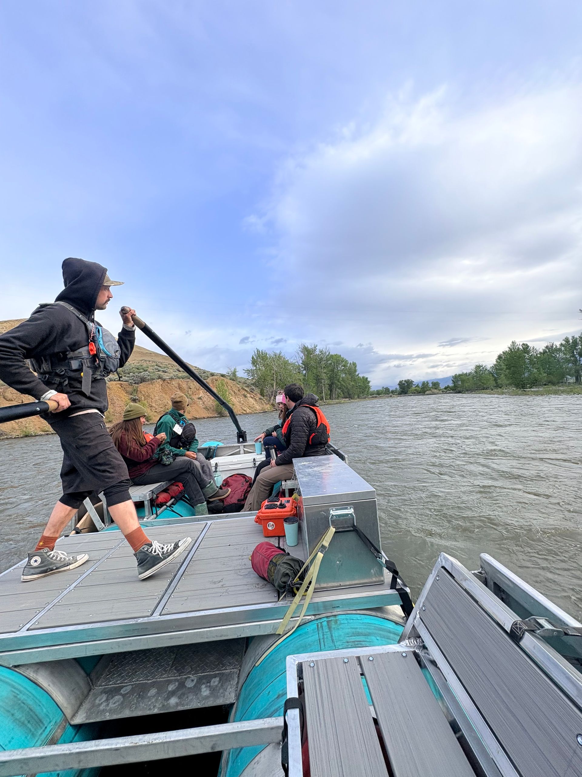 People on a metal boat crossing choppy water under a cloudy sky