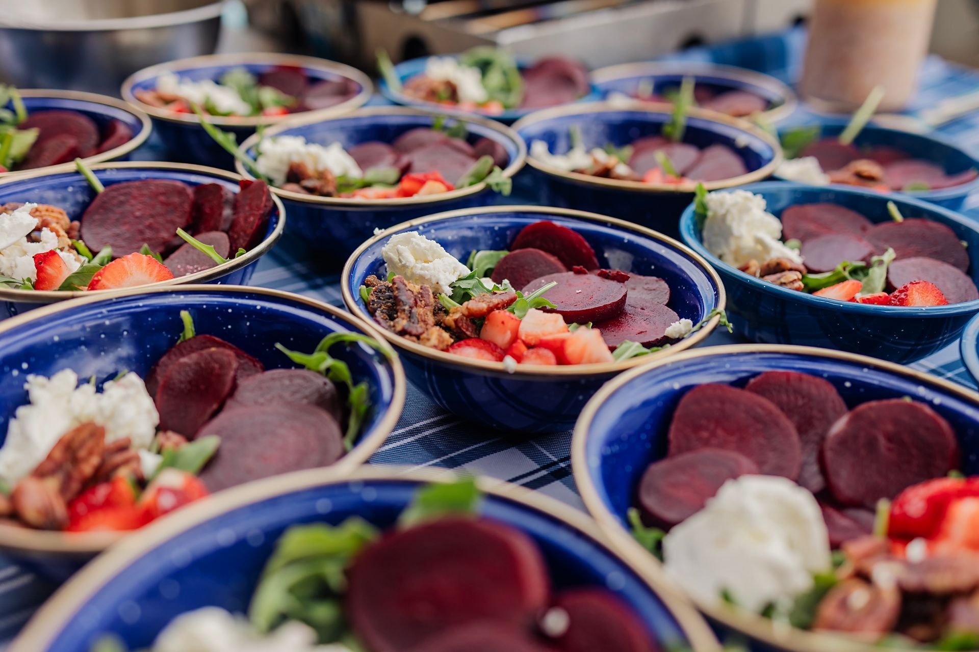 Rows of blue bowls filled with assorted poke, sliced tuna, avocado, and rice in a buffet setting