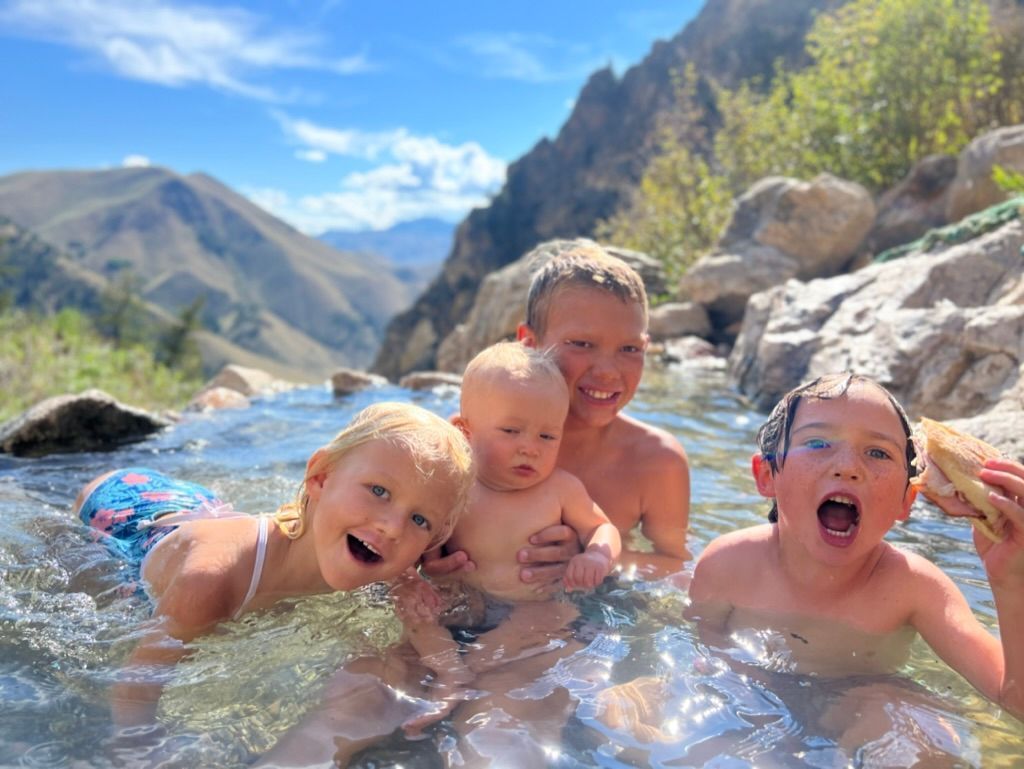 Four children splashing in a mountain stream on a sunny day