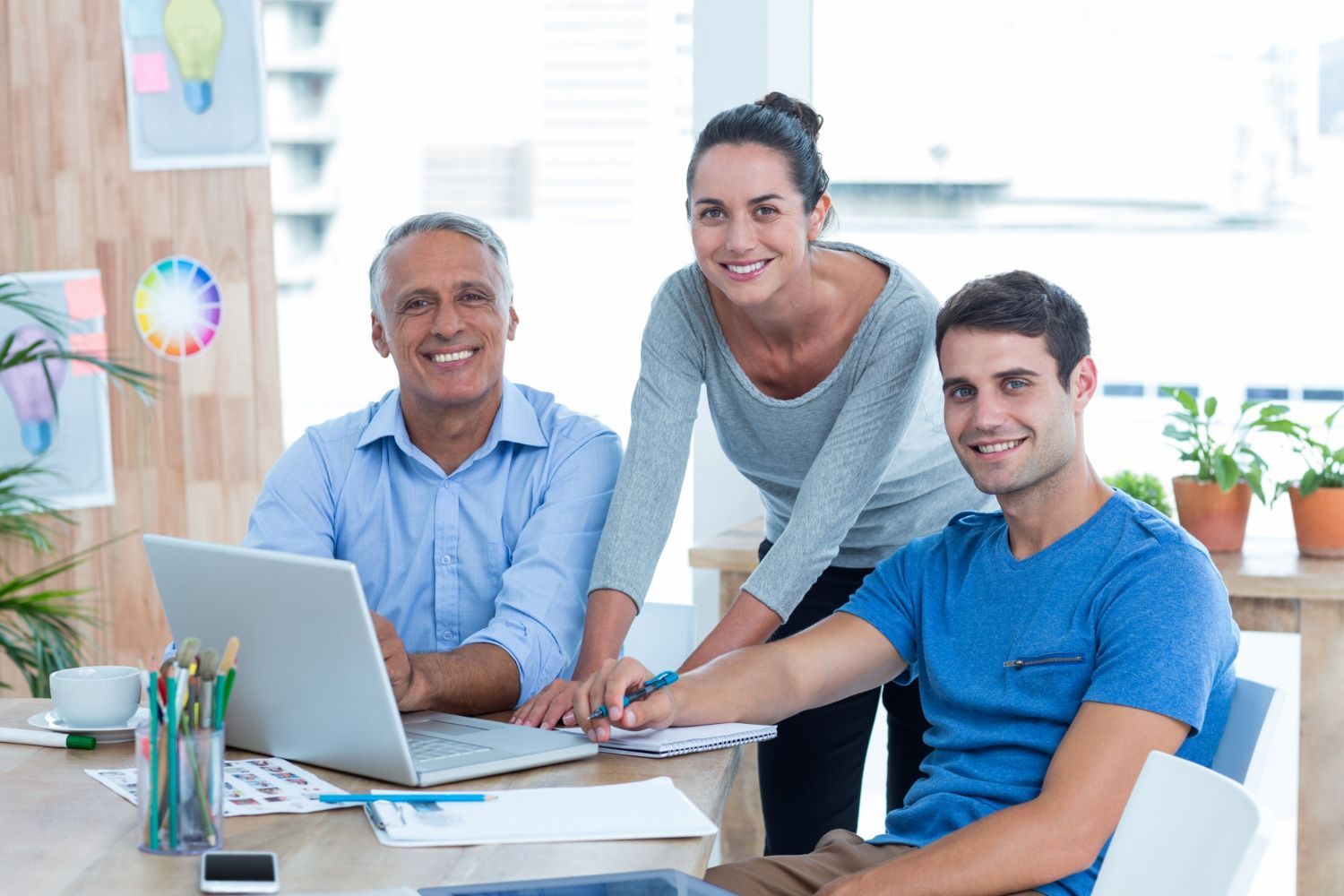 Un grupo de personas está sentado en una mesa con computadoras portátiles.