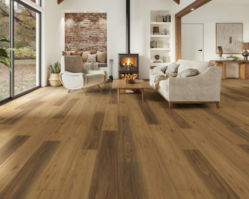 Wooden-floored living room with a fireplace, seating, and a large window overlooking a yard.