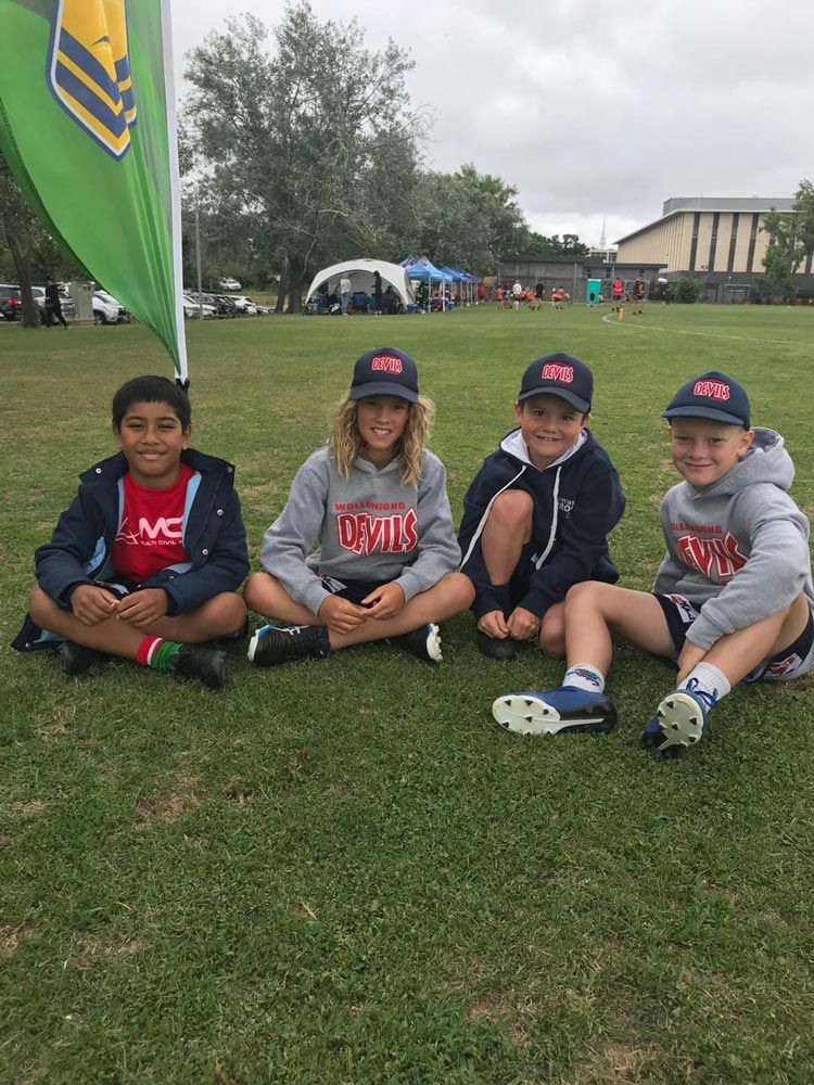 Kids Wearing Jacket Sitting On The Grass — Promotional Apparel In Woonona, NSW