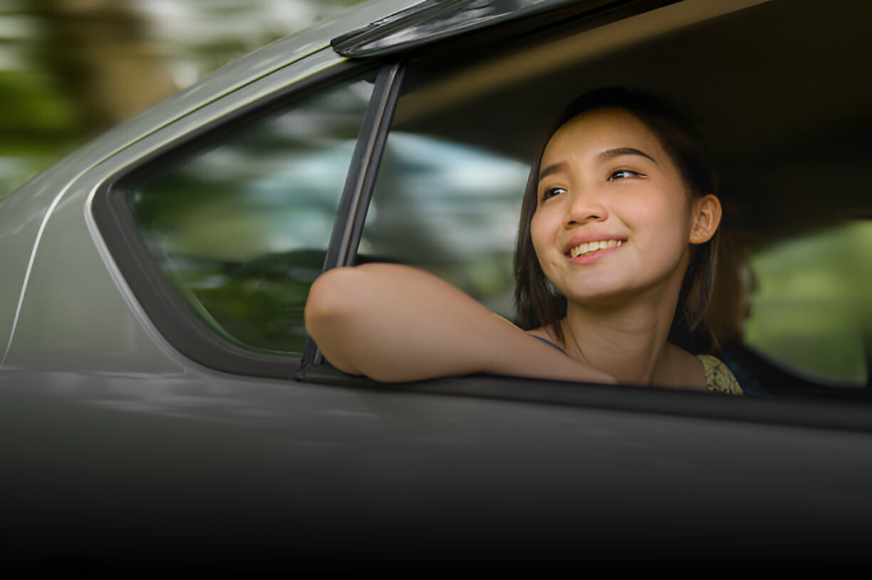 一名婦女坐在車裡,看著窗外。