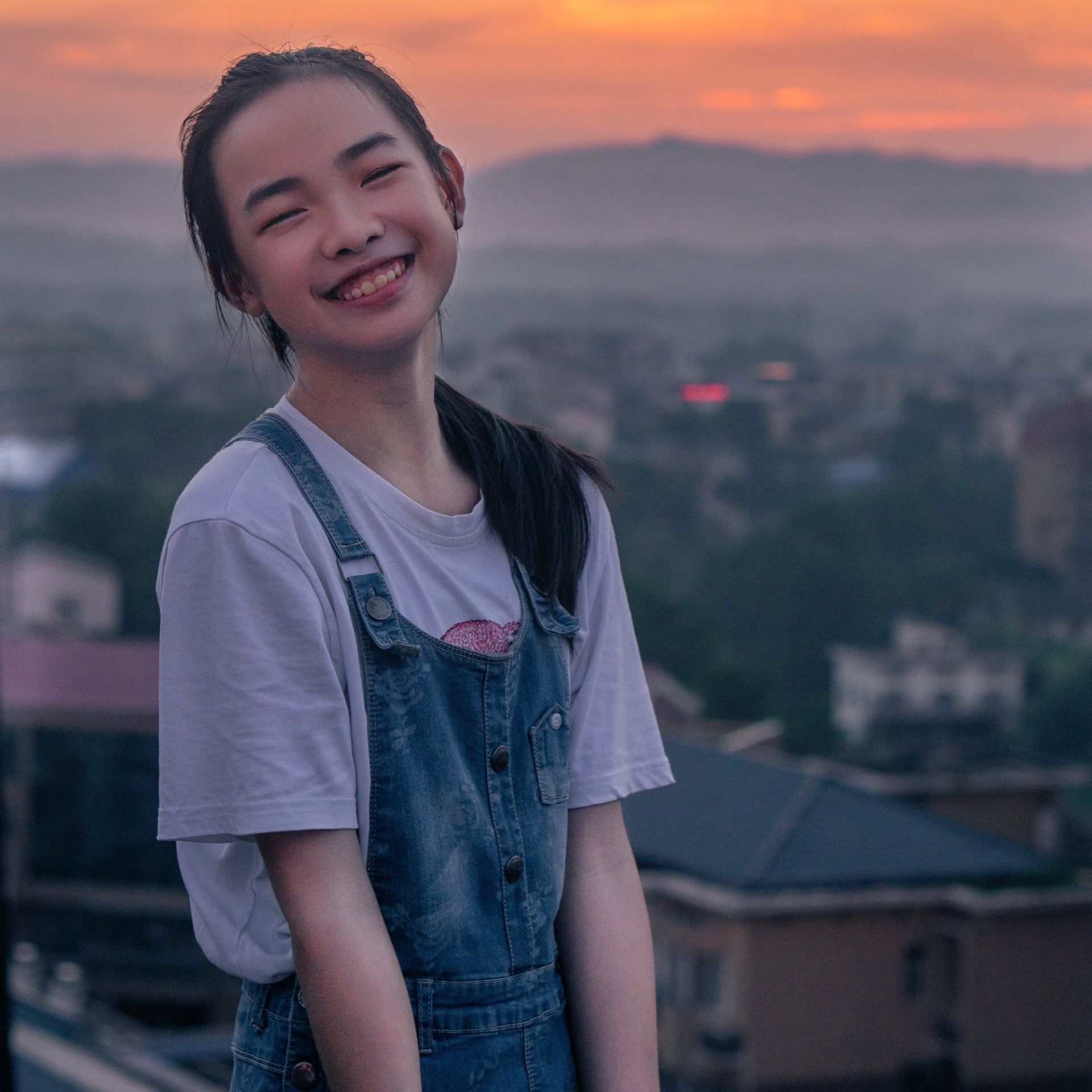 一位身穿工裝褲和白襯衫的小女孩微笑著