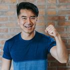 一名身穿藍色襯衫的男子正在磚牆前伸展手臂。