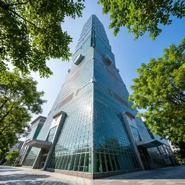 方形 photorealistic 圖片，採用創意低視角仰拍技术，從台北 101 大樓基座直上，幾何玻璃帷幕直插藍天。前景巧妙融合信義商圈路樹綠葉畫框，呈現竹節般高聳地標的國際脈動。