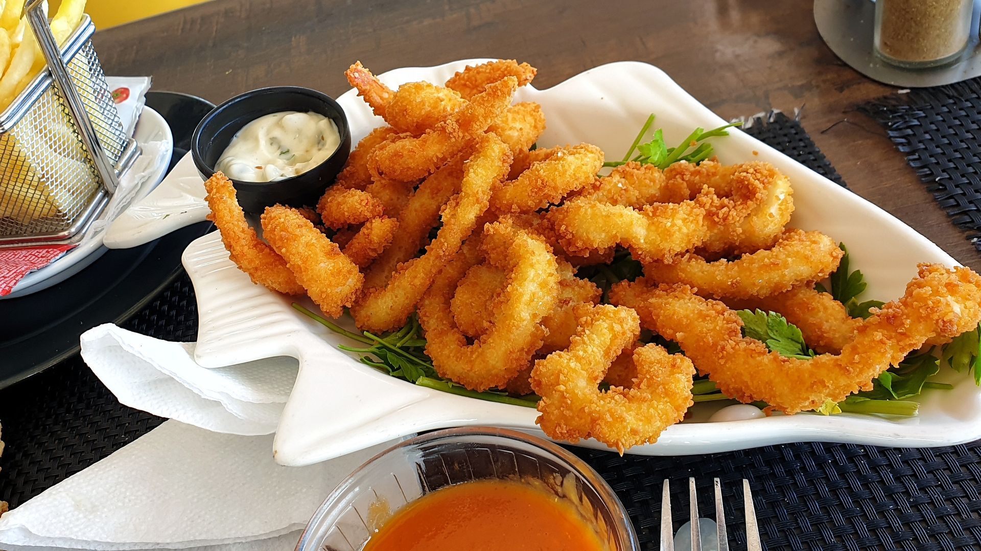 A white plate topped with fried shrimp and sauce on a table.