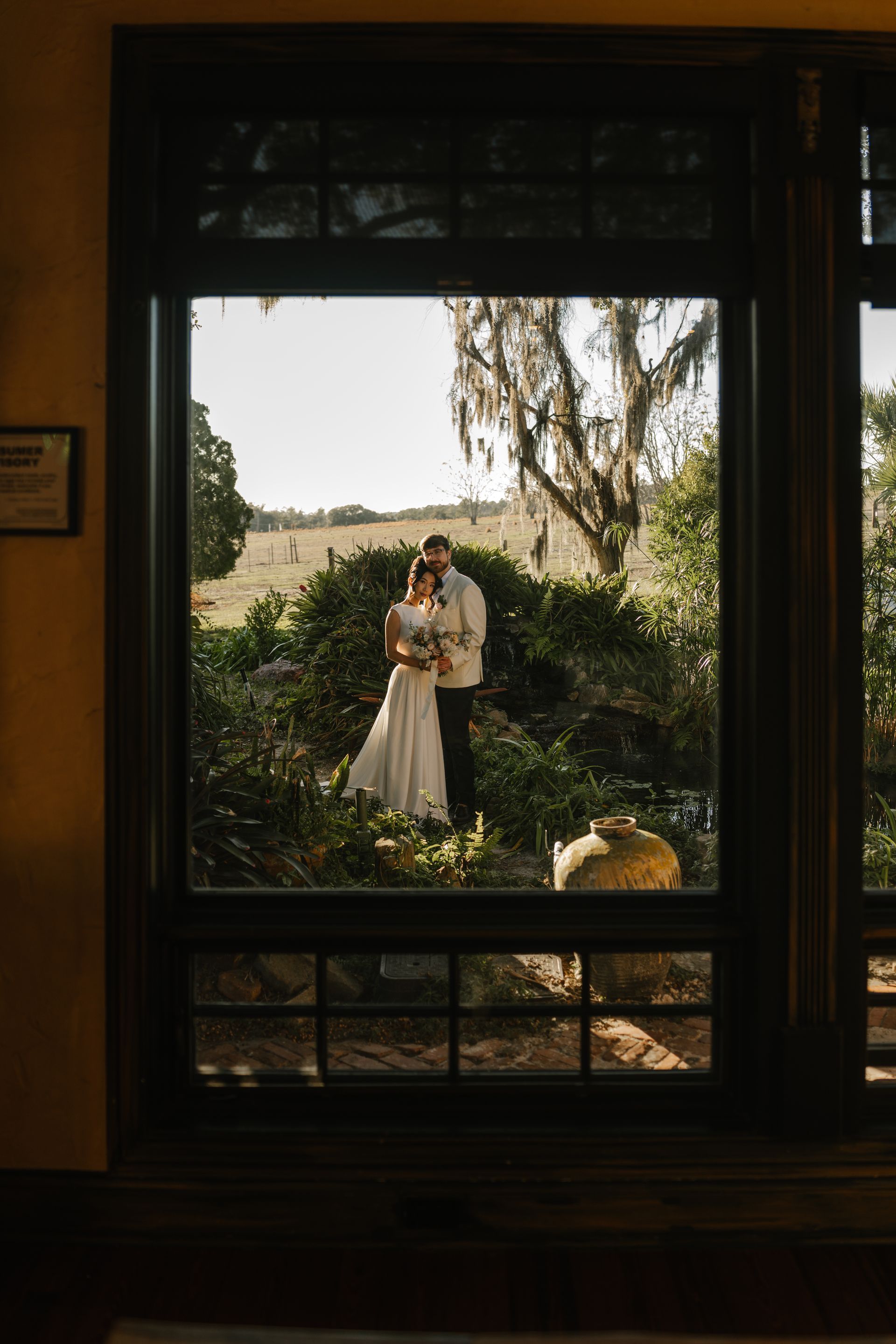 Bride and groom embracing in a garden with a koi pond