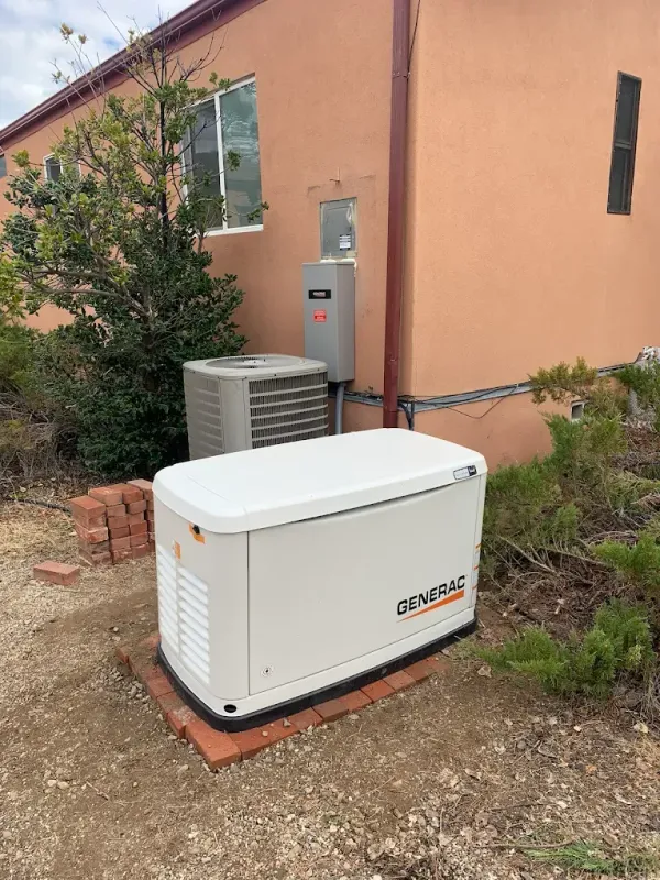 Rainwater harvesting system: white gutter draining into a brown tank next to a stucco wall.