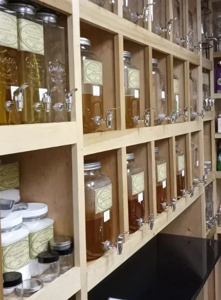 Wooden shelves with glass jars filled with liquids and spouts for dispensing.