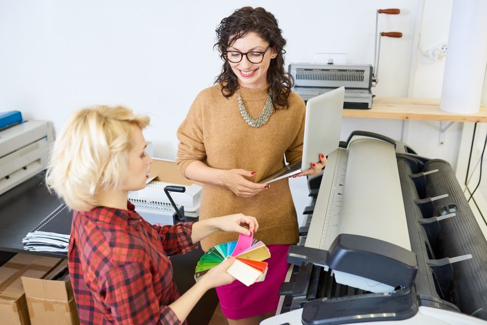Two Graphic Designers Standing By Printing Machine — Graphic Designer In Nowra, QLD
