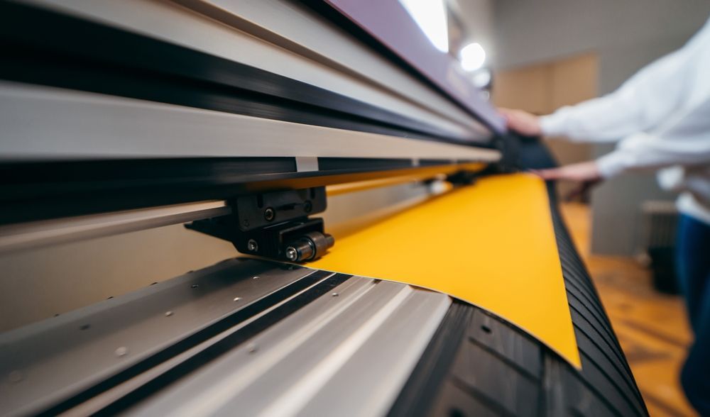 Hands Holding Yellow Printable Material — Graphic Designer In Airlie Beach, QLD
