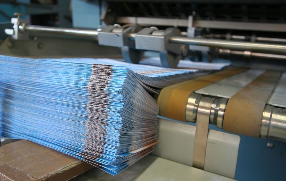 Working Print Machine With Brochure Pile — Graphic Designer In Airlie Beach, QLD