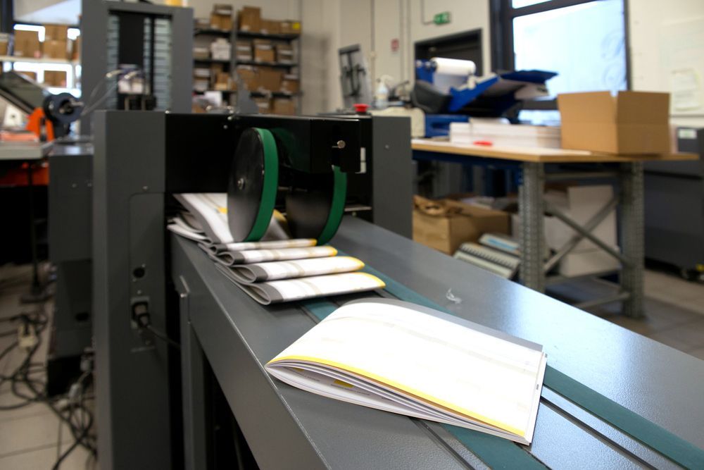 Brochures On The Finishing Line Machine — Graphic Designer In Airlie Beach, QLD