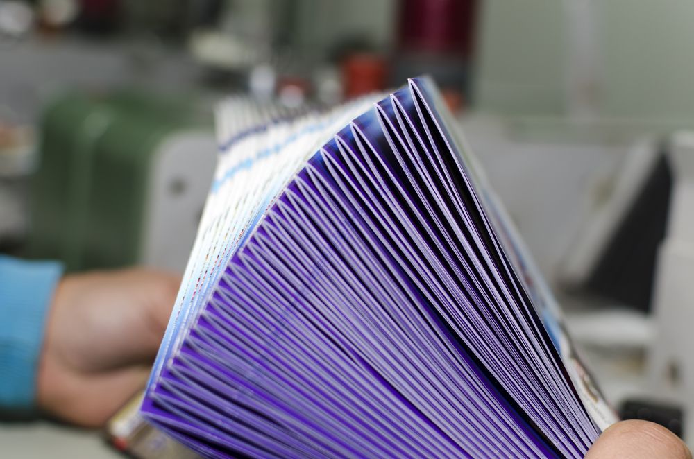 Man Holding A Pile Of Magazines — Graphic Designer In Airlie Beach, QLD