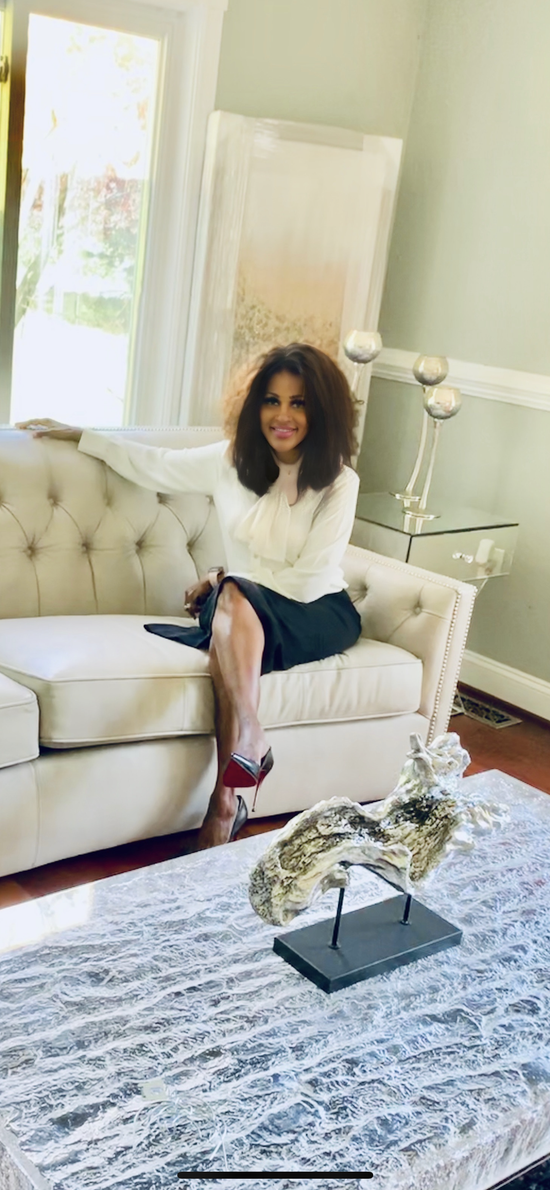 A woman is sitting on a couch in a living room next to a coffee table.