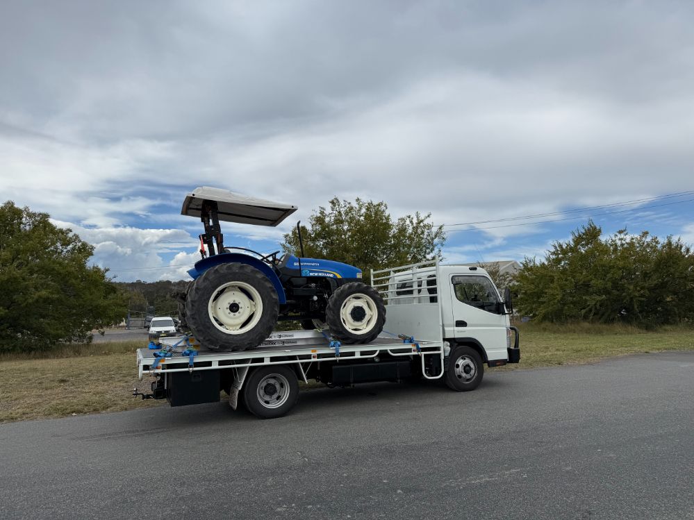 A Blue Tractor is on the Back of a Tow Truck — Goulburn Transport In Brisbane, QLD